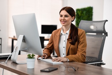 Photo of Woman working on computer at table in office