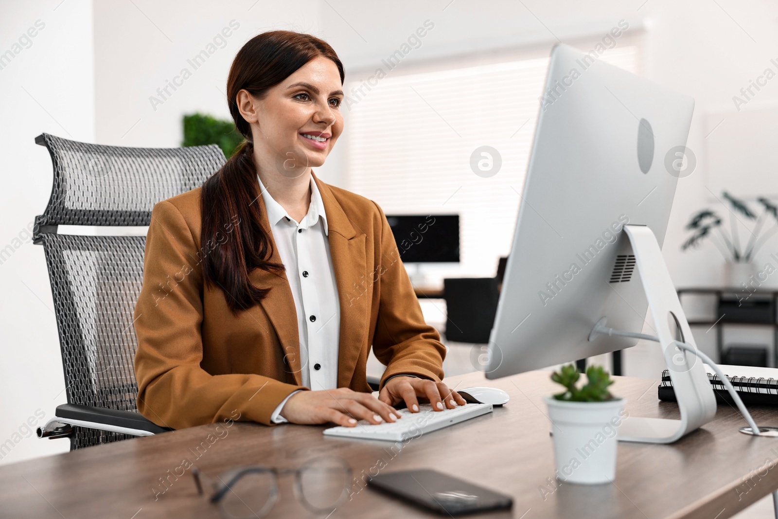 Photo of Woman working on computer at table in office