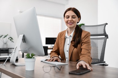 Photo of Woman working on computer at table in office