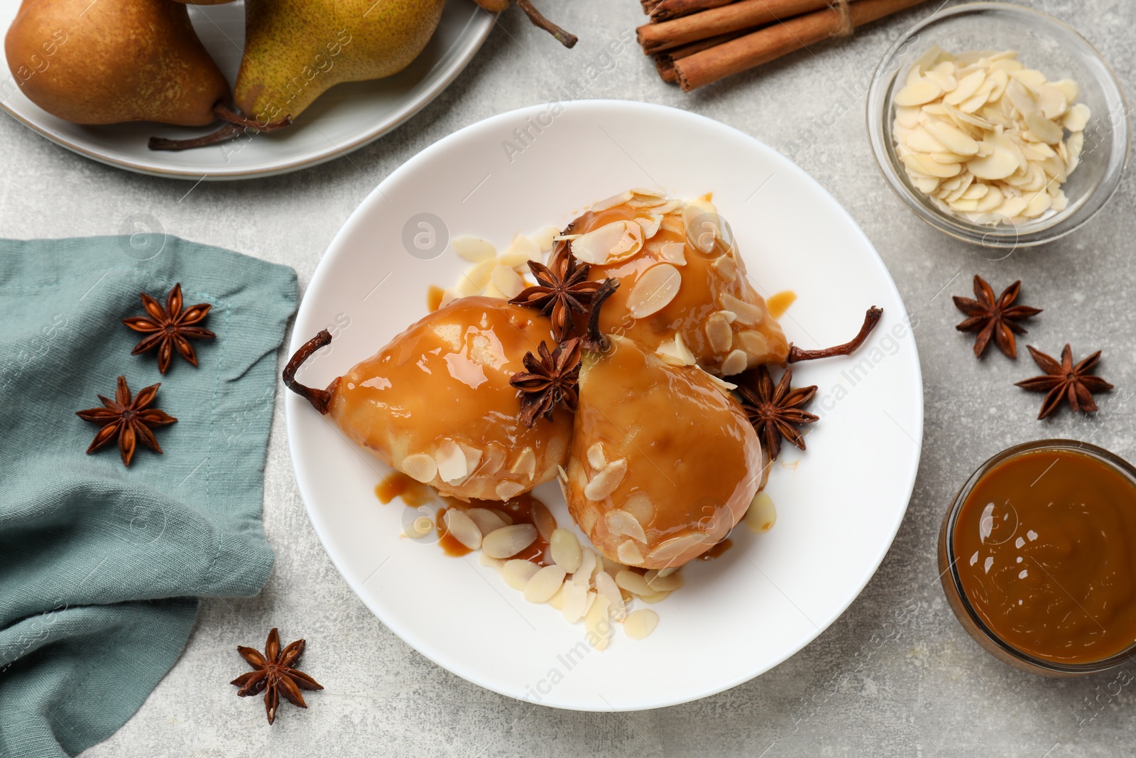 Photo of Delicious pears with caramel sauce, almond flakes and spices on grey table, top view