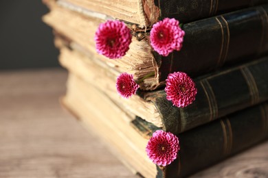 Photo of Stack of books and beautiful flowers on table, closeup