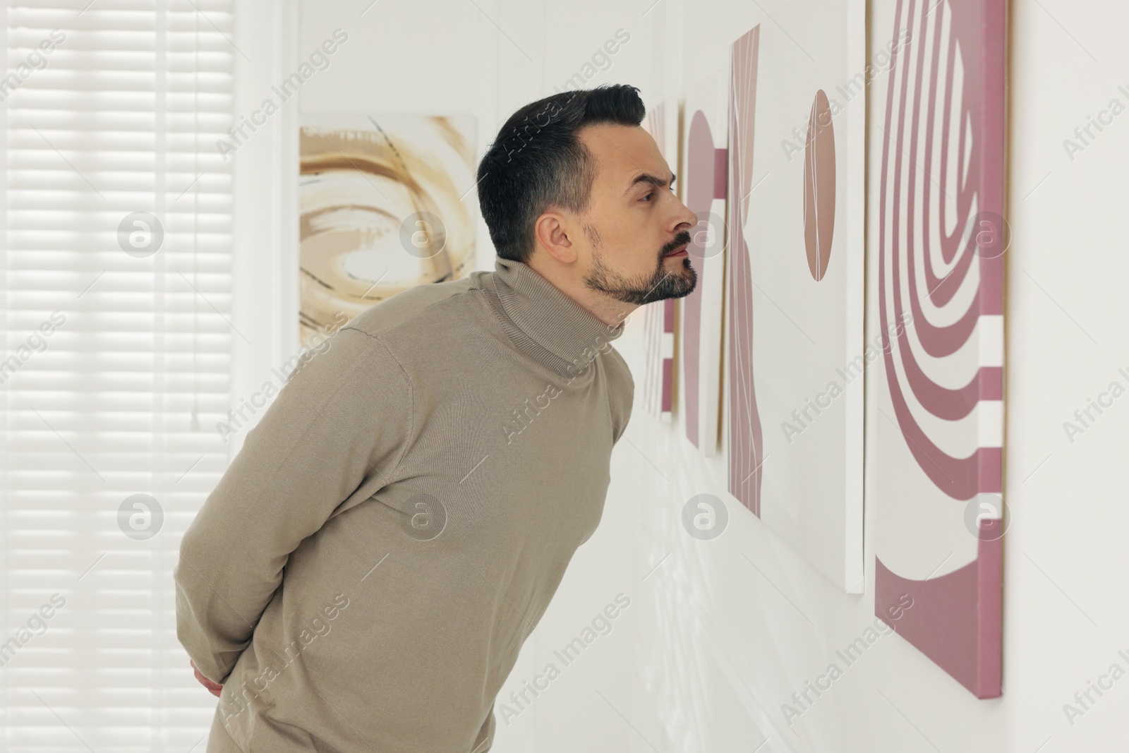 Photo of Man examining beautiful paintings in art gallery