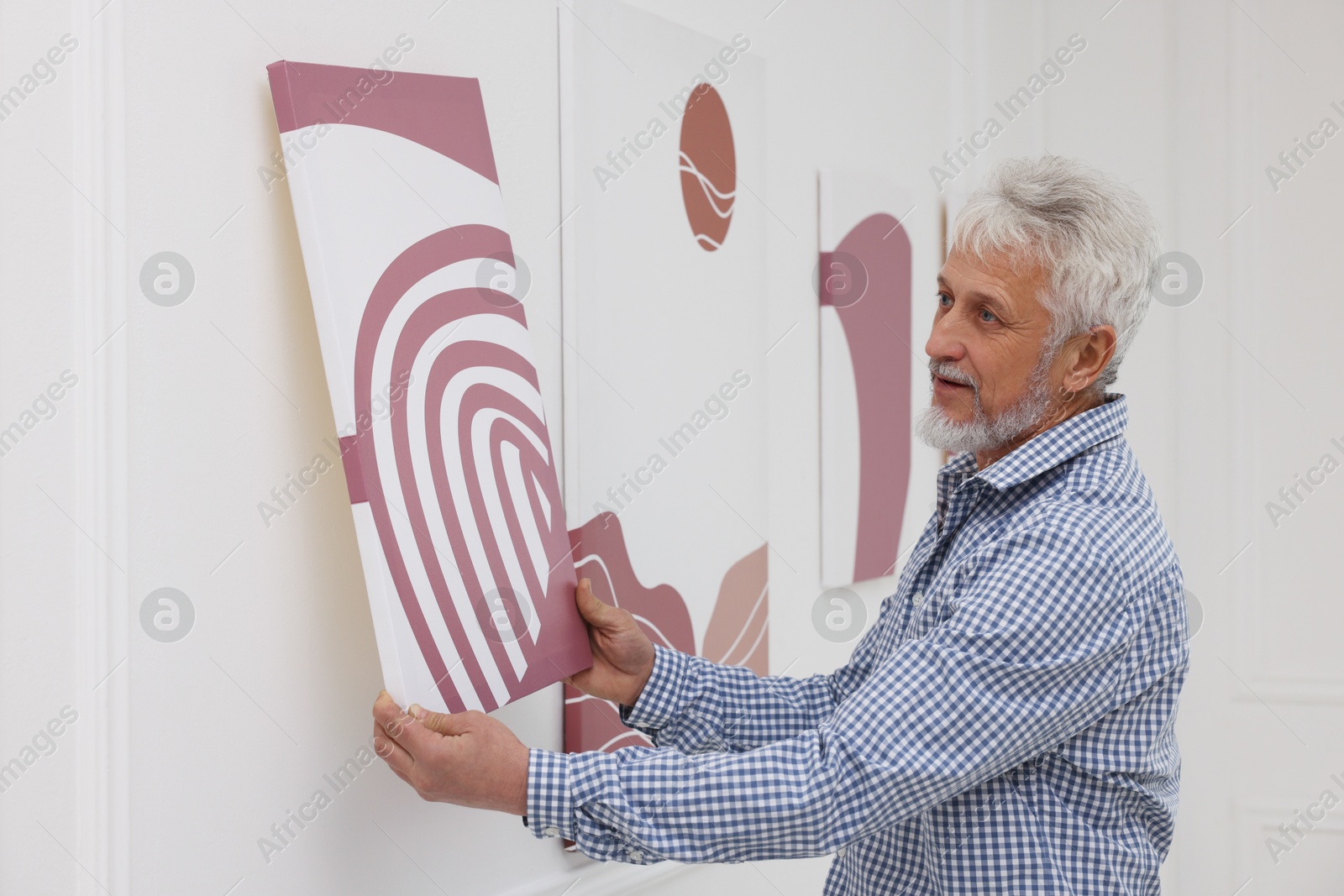 Photo of Man hanging painting on wall in art gallery