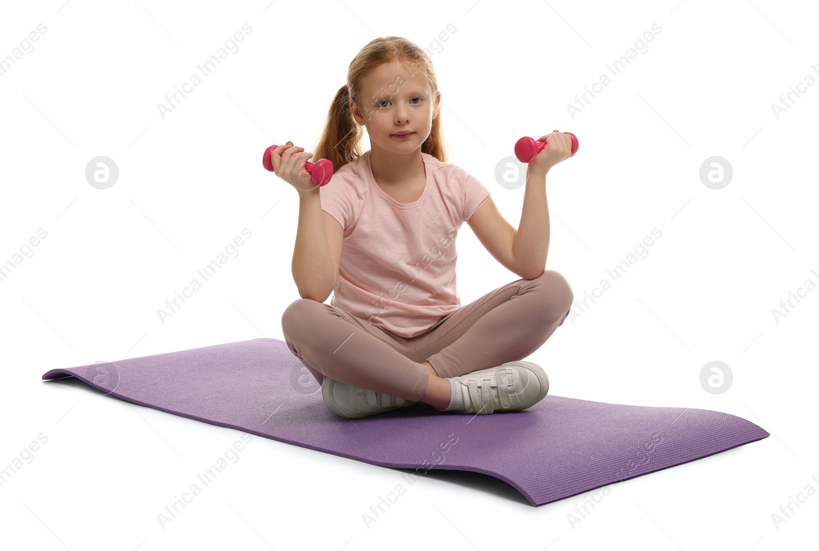 Photo of Cute little girl with dumbbells on fitness mat against white background