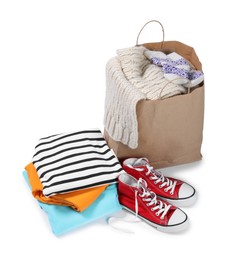 Photo of Bag with used clothes and sneakers isolated on white