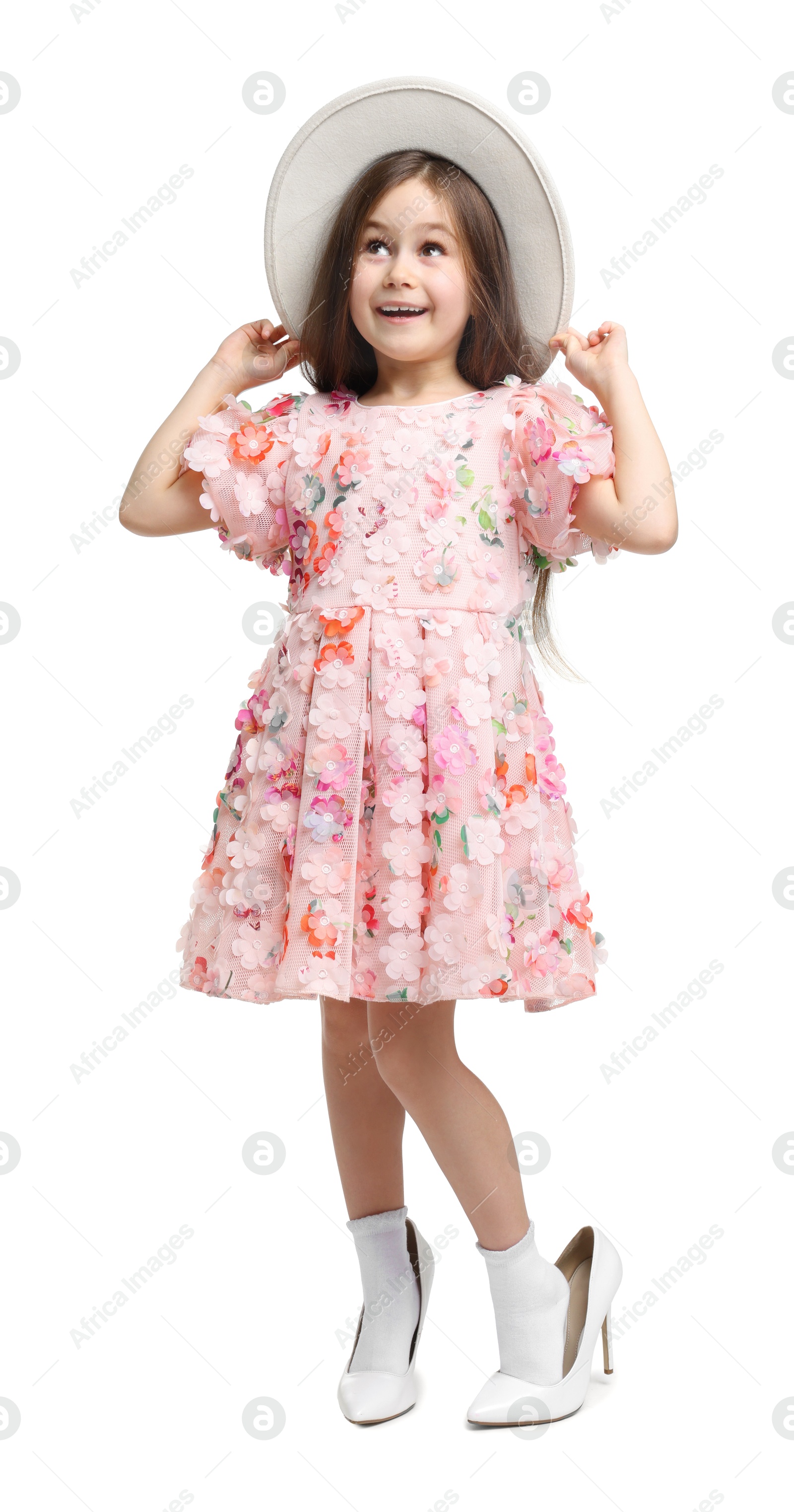 Photo of Stylish little girl wearing oversized high heeled shoes on white background