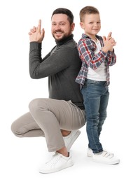 Happy father with his cute little son making finger gun gesture on white background