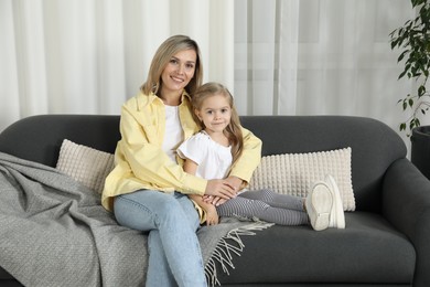 Happy mother and her cute little daughter on sofa at home