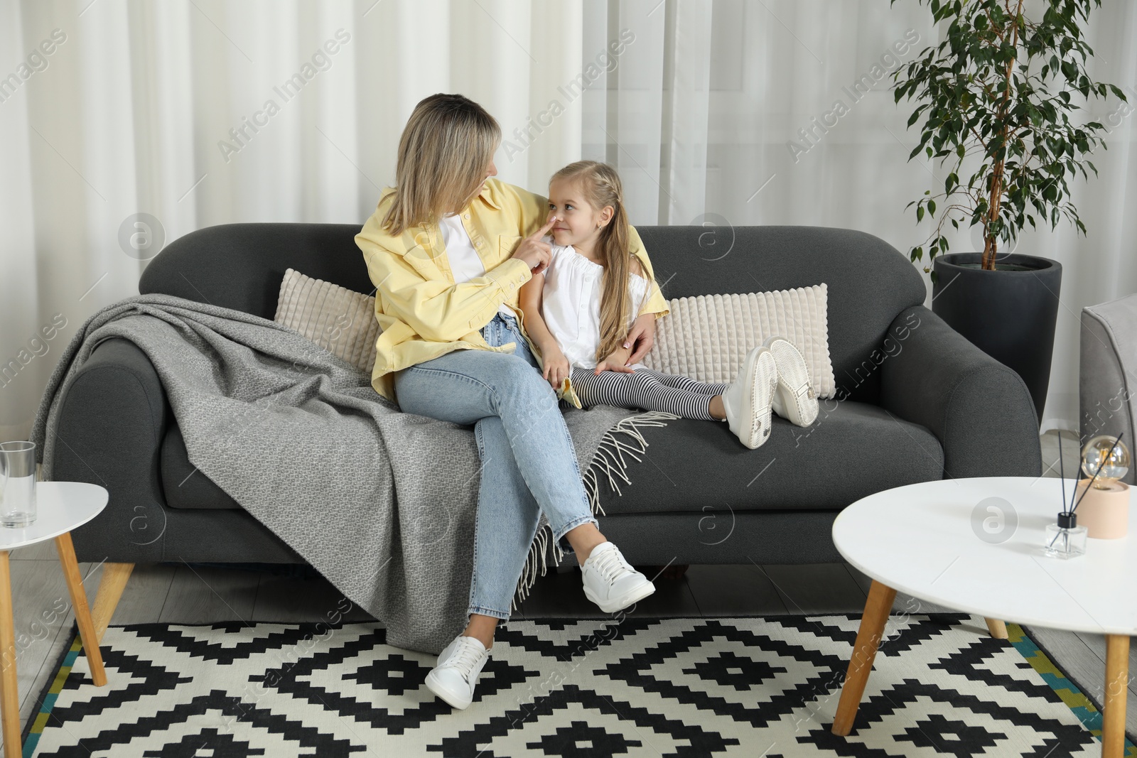 Photo of Mother and her cute little daughter on sofa at home