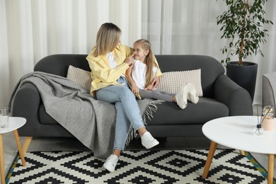 Mother and her cute little daughter on sofa at home