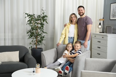 Happy parents and their children in armchair at home