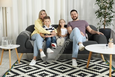 Happy parents and their children on sofa at home