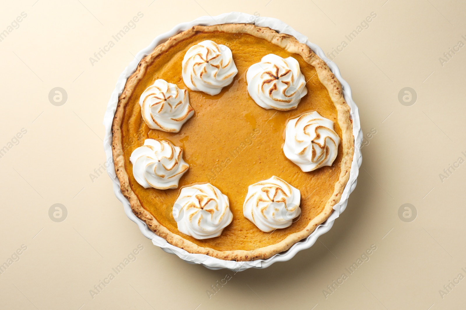 Photo of Tasty homemade pumpkin pie in baking dish on beige table, top view