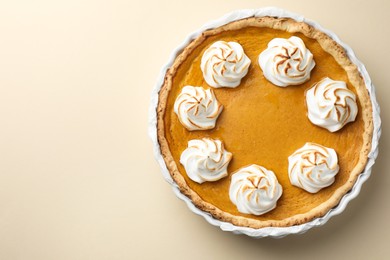 Photo of Tasty homemade pumpkin pie in baking dish on beige table, top view. Space for text