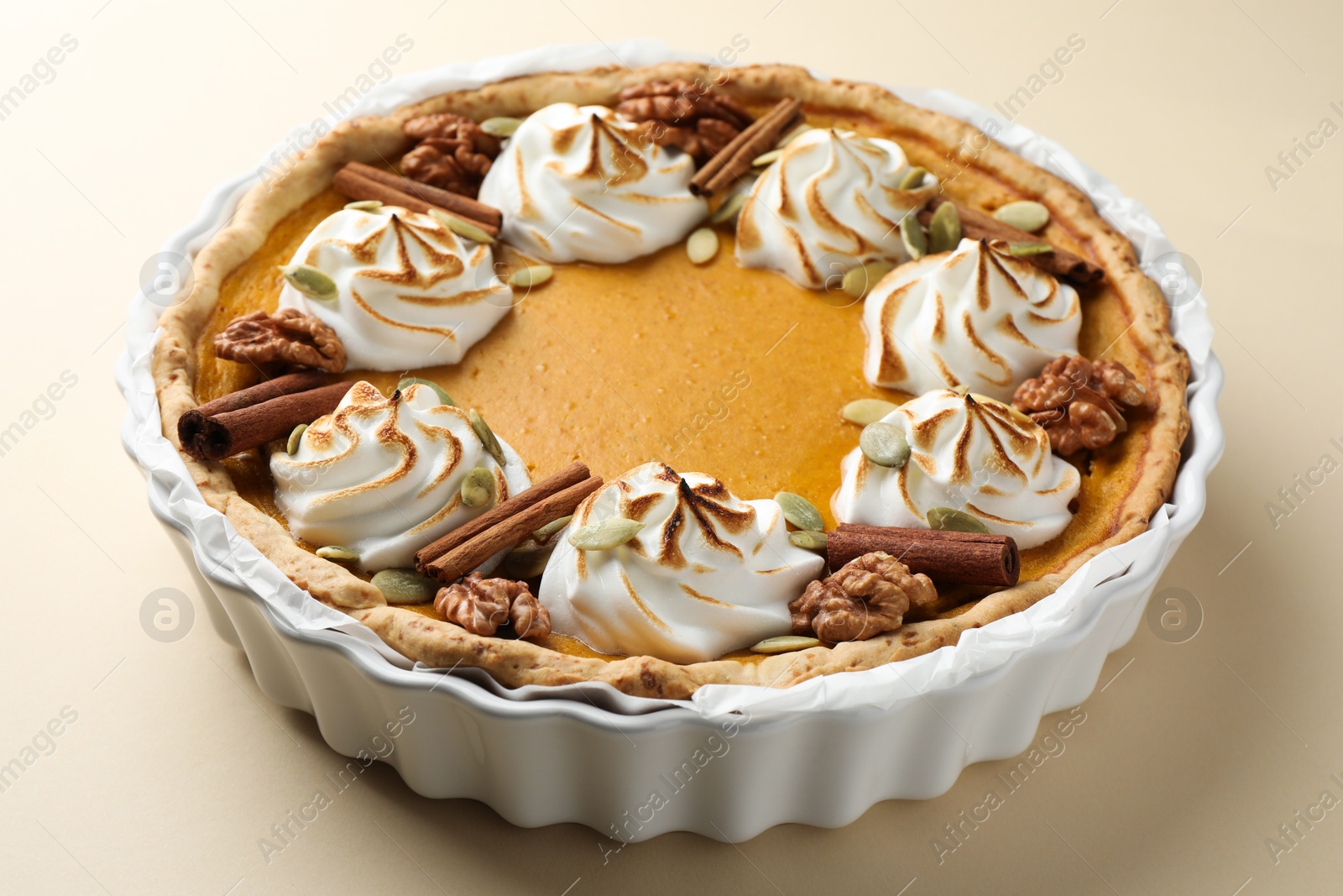 Photo of Tasty homemade pumpkin pie in baking dish on beige table, closeup