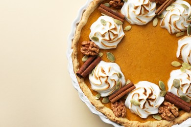 Photo of Tasty homemade pumpkin pie in baking dish on beige table, top view. Space for text