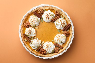 Photo of Delicious homemade pumpkin pie in baking dish on orange table, top view