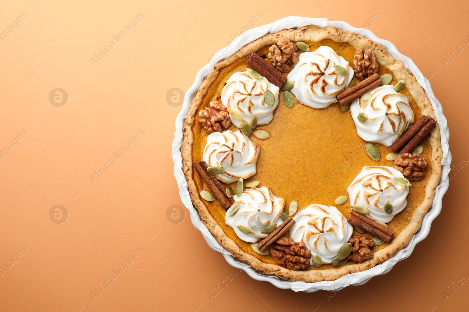 Photo of Delicious homemade pumpkin pie in baking dish on orange table, top view. Space for text