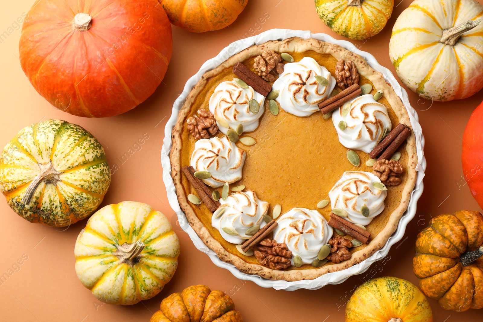 Photo of Delicious homemade pumpkin pie in baking dish and fresh pumpkins on orange table, flat lay