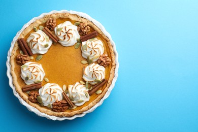 Photo of Tasty homemade pumpkin pie in baking dish on light blue table, top view. Space for text