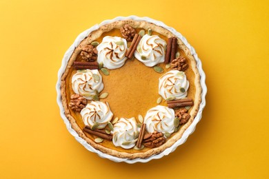 Photo of Tasty homemade pumpkin pie in baking dish on orange table, top view