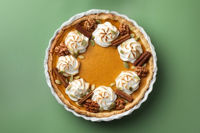 Photo of Tasty homemade pumpkin pie in baking dish on green table, top view