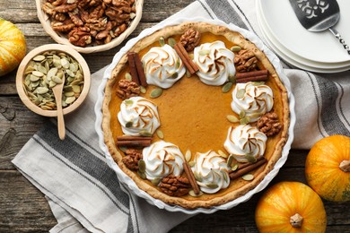 Photo of Tasty homemade pumpkin pie in baking dish and ingredients on wooden table, flat lay