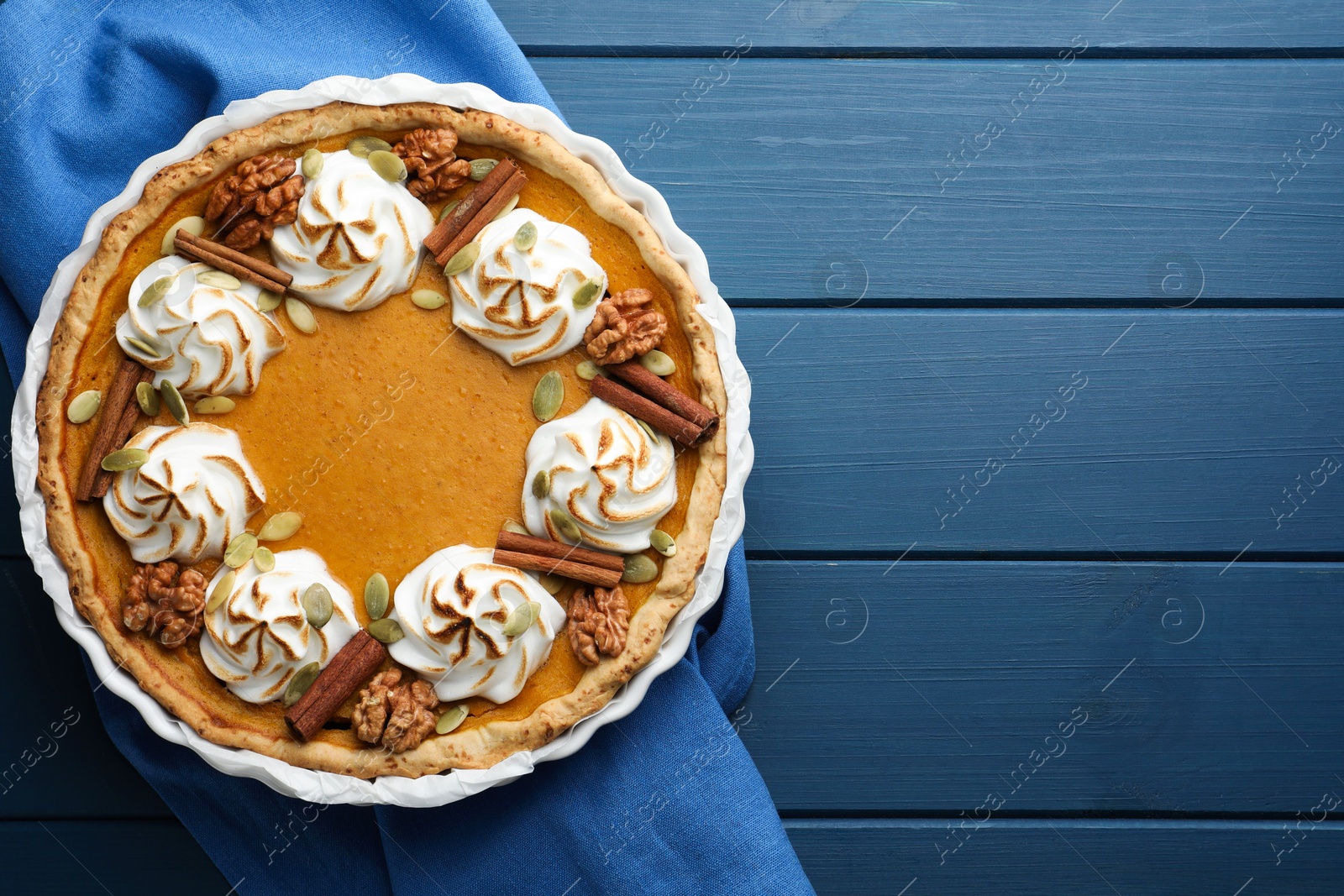 Photo of Delicious homemade pumpkin pie in baking dish on blue wooden table, top view. Space for text