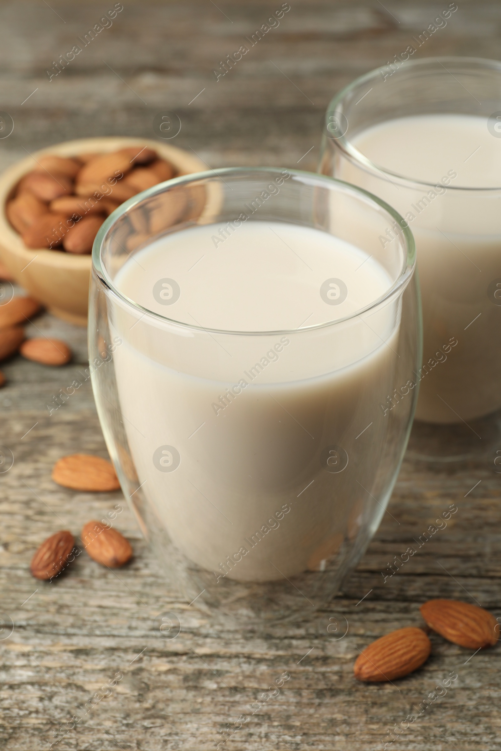 Photo of Fresh nut milk in glasses and almonds on wooden table, closeup