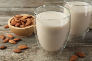 Photo of Fresh nut milk in glasses and almonds on wooden table, closeup