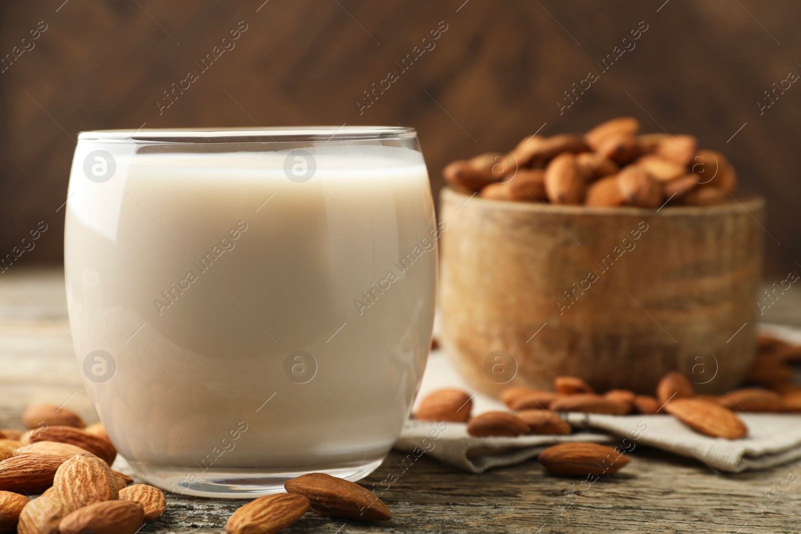 Photo of Fresh almond milk in glass and nuts on wooden table, closeup