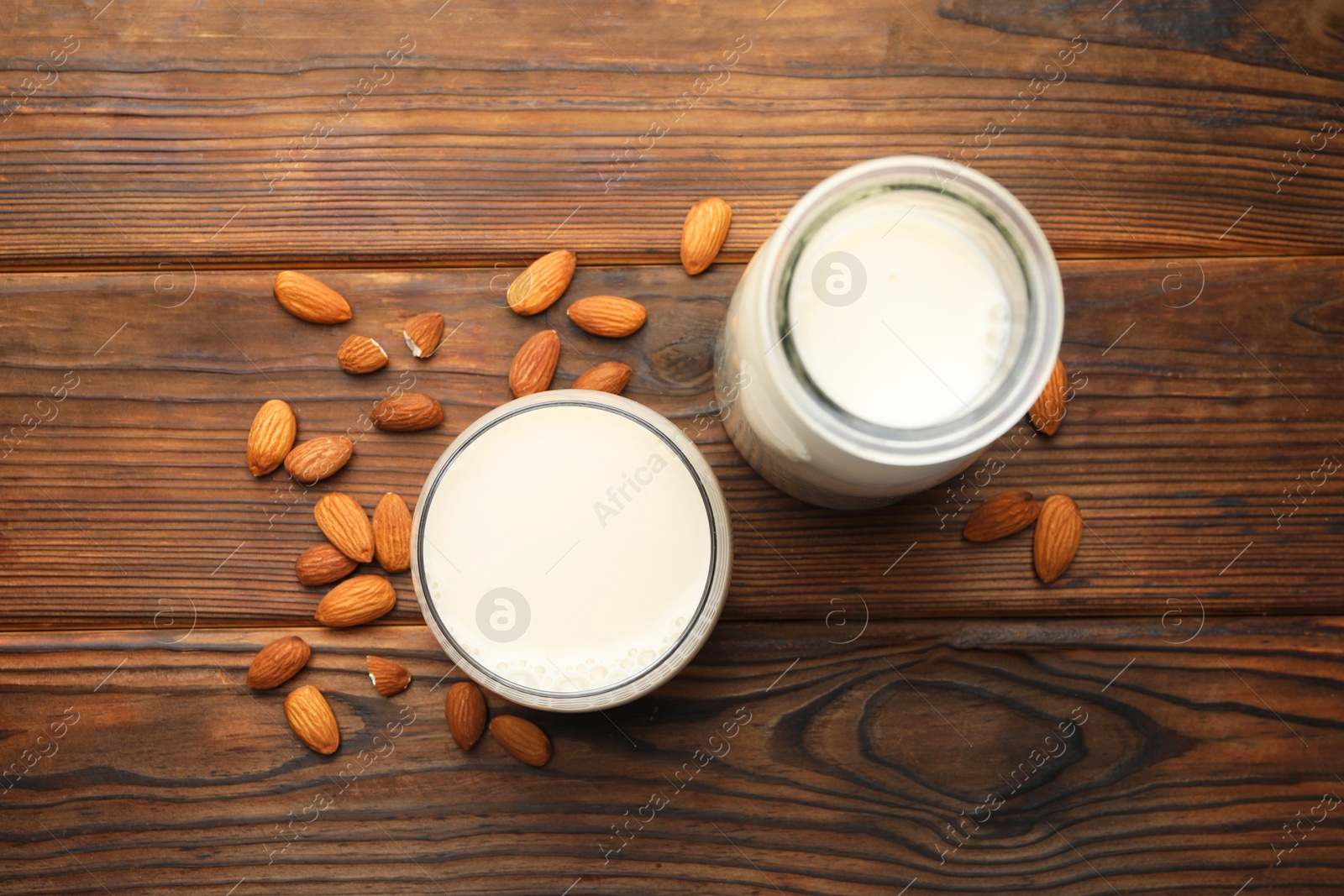 Photo of Fresh almond milk and nuts on wooden table, top view