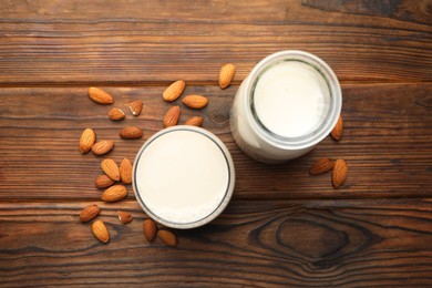 Fresh almond milk and nuts on wooden table, top view