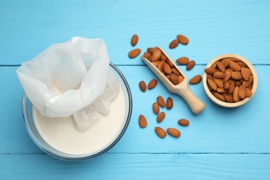 Homemade almond milk, cheesecloth with mixture and nuts on light blue wooden table, top view