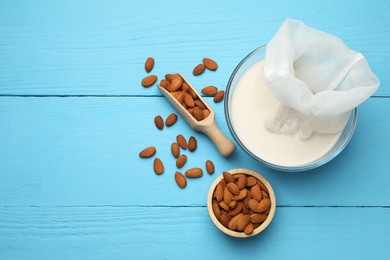 Photo of Homemade almond milk, cheesecloth with mixture and nuts on light blue wooden table, top view. Space for text