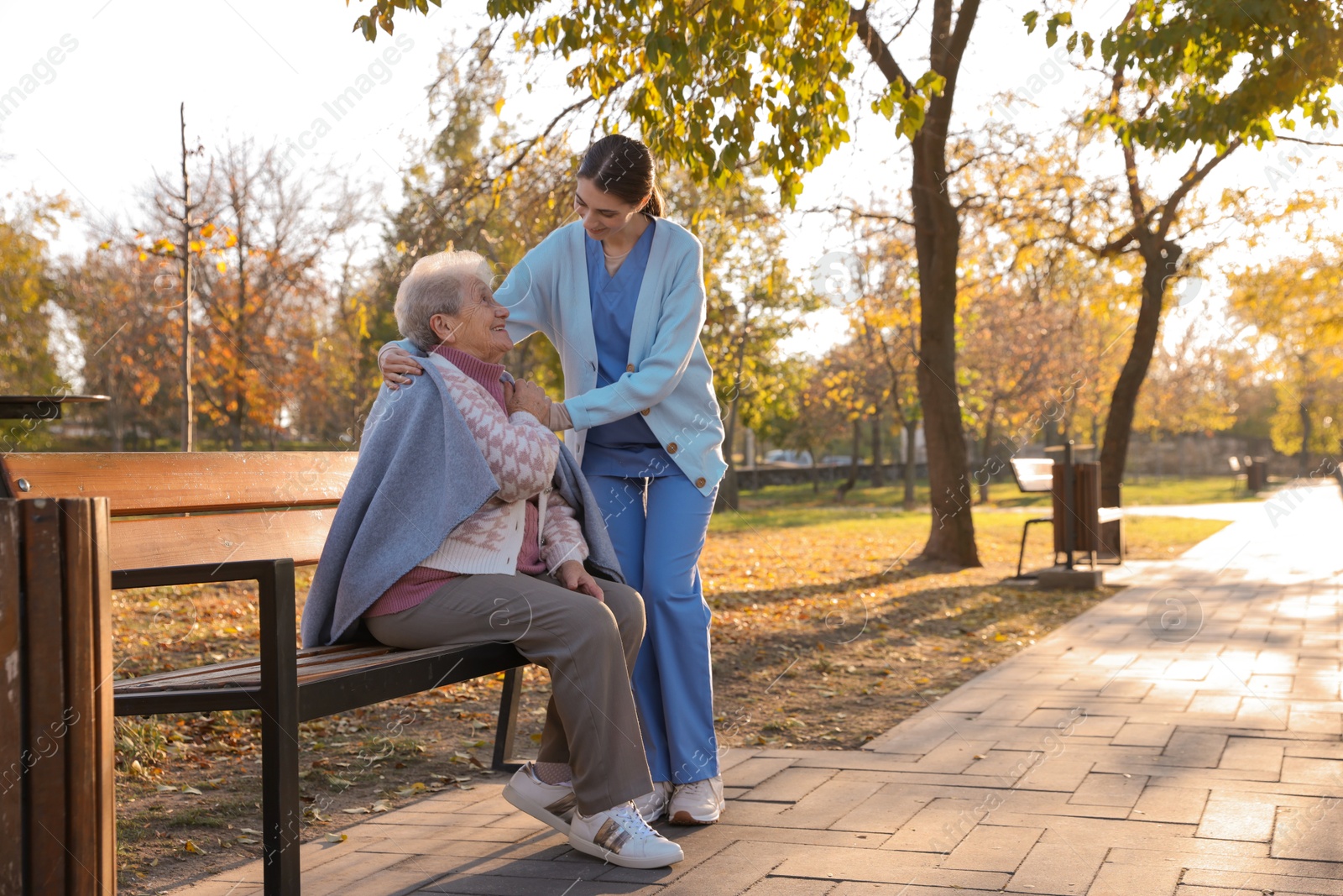 Photo of Elderly woman with her caregiver in park. Space for text