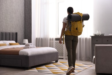 Photo of Traveller with backpack in hotel room, back view