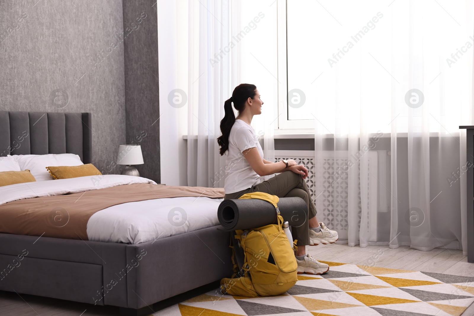 Photo of Traveller with backpack sitting on bed in hotel room