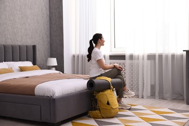 Photo of Traveller with backpack sitting on bed in hotel room