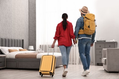 Photo of Travellers with suitcase and backpack in hotel room, back view