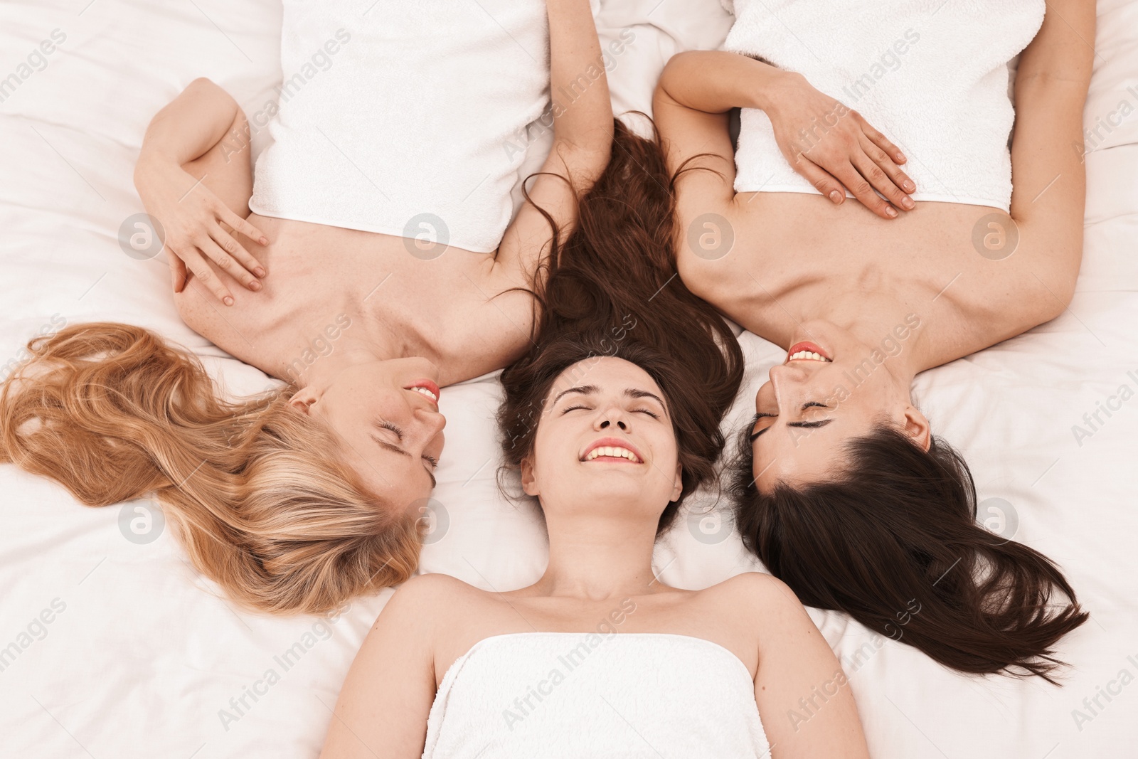 Photo of Spa day. Happy women lying on bed, above view