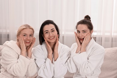 Happy woman wearing bathrobes on sofa in spa