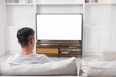 Photo of Man watching TV on sofa at home, back view