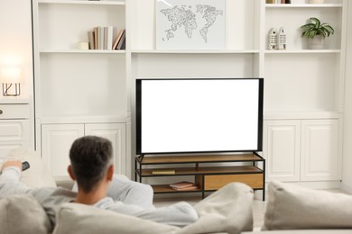 Photo of Man watching TV on sofa at home, back view