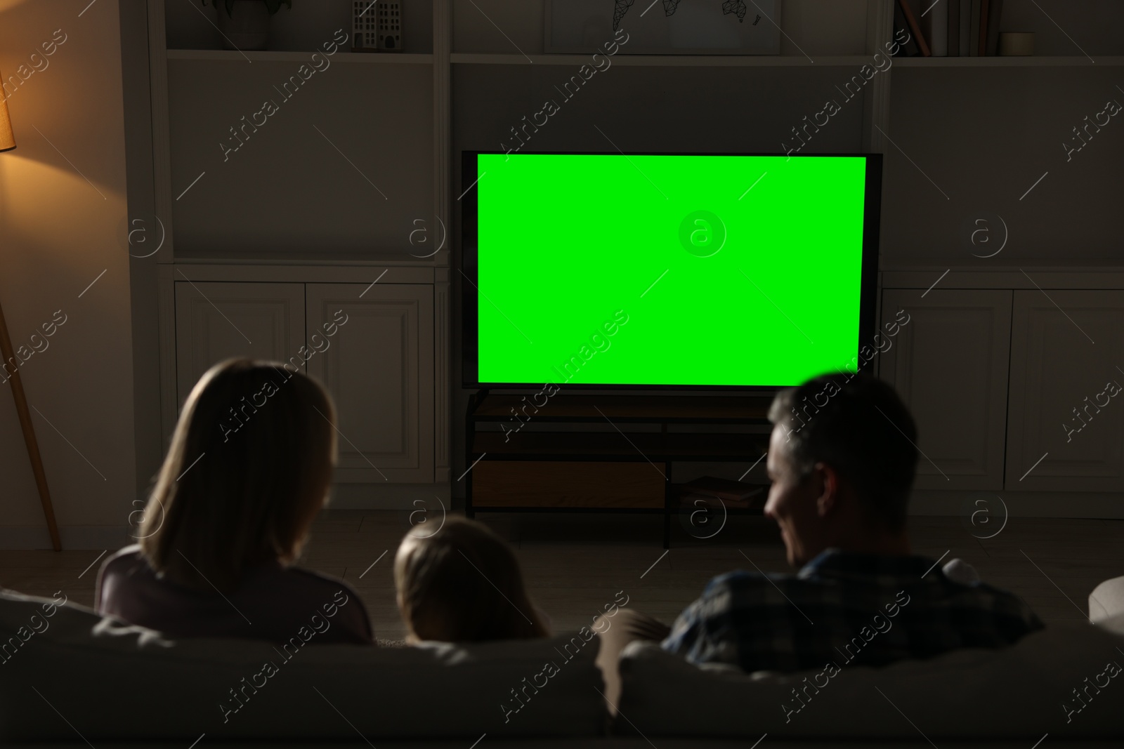 Photo of Family watching TV on sofa at home in evening