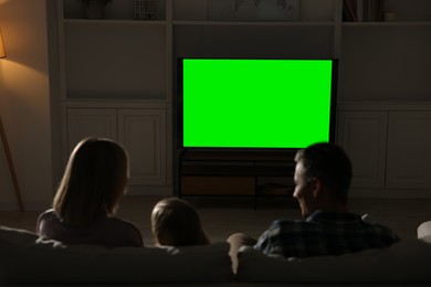 Photo of Family watching TV on sofa at home in evening