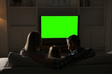 Photo of Family watching TV on sofa at home in evening