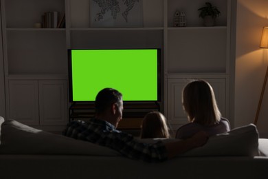 Photo of Family watching TV on sofa at home in evening