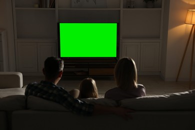 Family watching TV on sofa at home in evening, back view