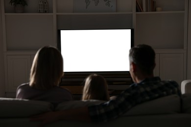 Family watching TV on sofa at home in evening, back view